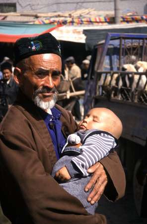 photo of China, Xinjiang province (East Turkistan), Kashi, old Uygur man with baby on the Kashgar Sunday market