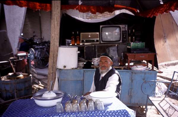 photo of China, Xinjiang province (East Turkistan), Kashi, old Uygur man in little street snack restaurant on the Kashgar Sunday market