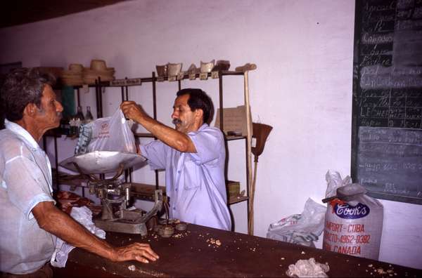 photo of West Cuba, Cuban man buying in a state shop. The goods in state shops are of poor quality and their number is very limited, but they are also very cheap. In the bigger towns most Western products are available for expensive dollars