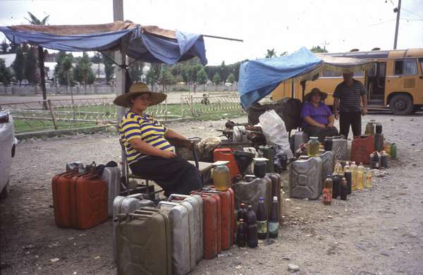 photo of Republic of Georgia, Zugdidi, Georgian woman with straw hats selling engine oil and fuel from bottles and jerrycans