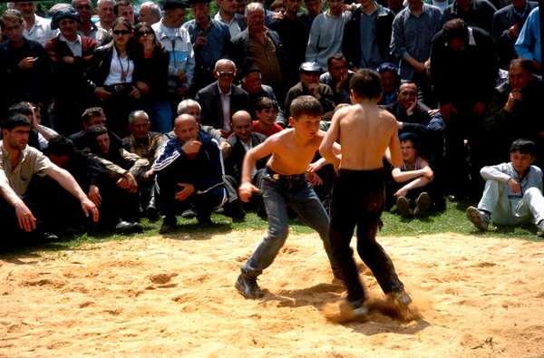 photo of Republic of Georgia, Kakheti, kids wrestling during the festival of Kochioba surrounded by a crowd of Georgian men