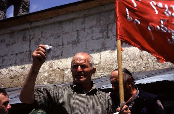 photo of Republic of Georgia, Svaneti, village of Kala, in front of St. Kvirike church, priest shouting the names of the people that want to be blessed. Villagers attending the Kvirikoba festival write their names on little papers which the priest collects and reads aloud