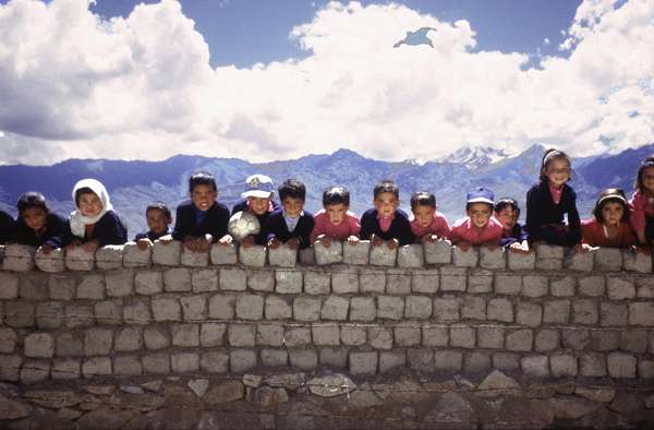 photo of India, Ladakh, around Leh, children with football looking over a stone wall