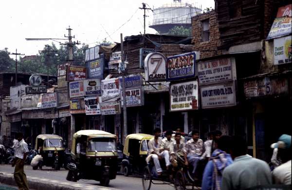 photo of India, New Delhi, street with rikshas and houses with billboards