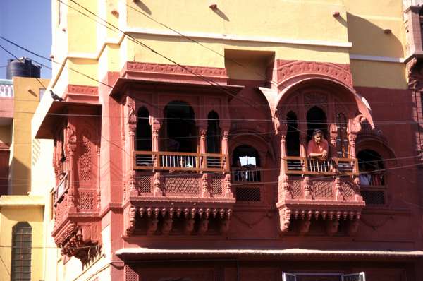 photo of India, Rajasthan, Bikaner, red and yellow house with woman