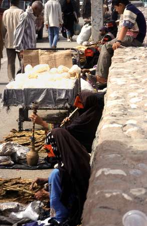 photo of Iran, Persian sea coast, around Bandar Abbas, Thursday market in Minab, man selling popcorn and women with red burqa (borqa) masks selling dried tobacco leaves