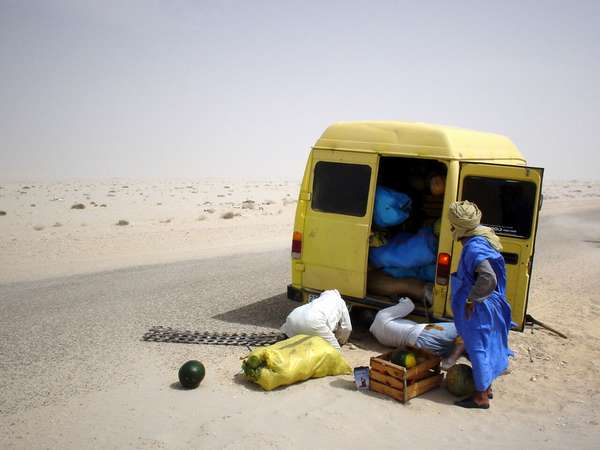 photo of Mauritania, yellow truck with Mauritanians in blue bobo, having a breakdown on the desert road between Western Sahara and the Mauritanian border