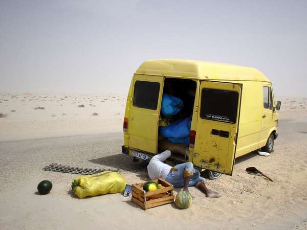 photo of Mauritania, yellow truck with Mauritanians in blue bobo, having a breakdown on the desert road between Western Sahara and the Mauritanian border