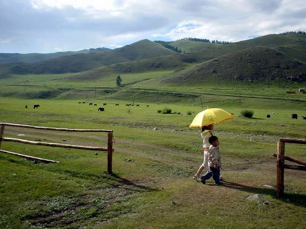 photo of Mongolia; around Terelj, hilly Mongolian landscape with two children and a yellow umbrella