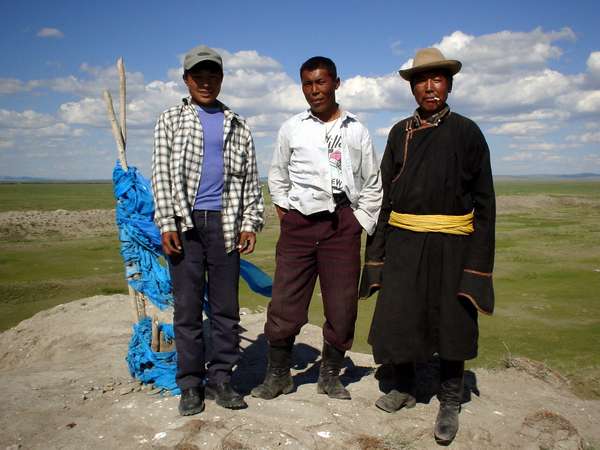 photo of Central Mongolia, three Mongolians with blue shamanic prayer flags and the Mongolian steppe in the background