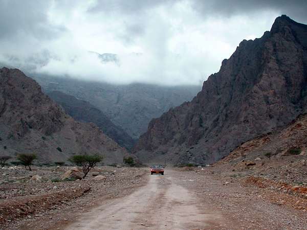 photo of Oman, Musandam peninsula, car on a dirt track road between rugged mountains