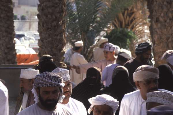 photo of Oman, Cattle and Animal market in Nizwa, Omanis between the date palms. All Omani wear their traditional white Arabic dress, the dishdasha (thobe) and embroidered skull cap called a kumma