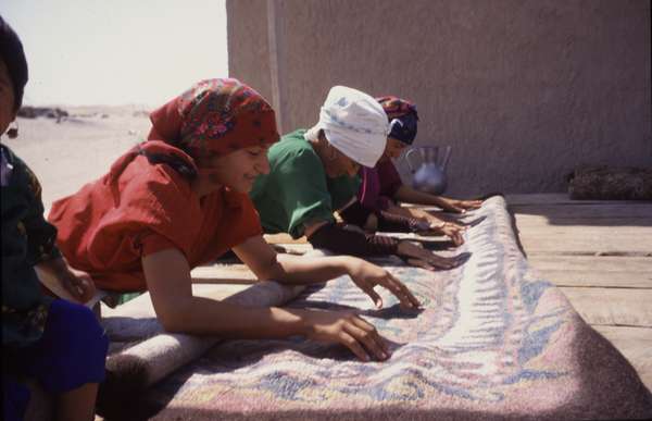 photo of Turkmenistan, Kara Kum desert, Yerbent (Jerbent), Turkmen women rolling a wool carpet