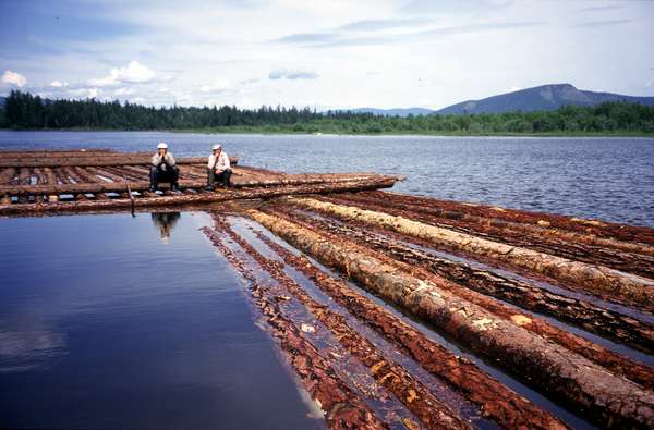 photo of Tuva, between Kyzyl and Toora Khem, two timber workers sitting on tree trunks floating in the Yenisei (Yenisey) river