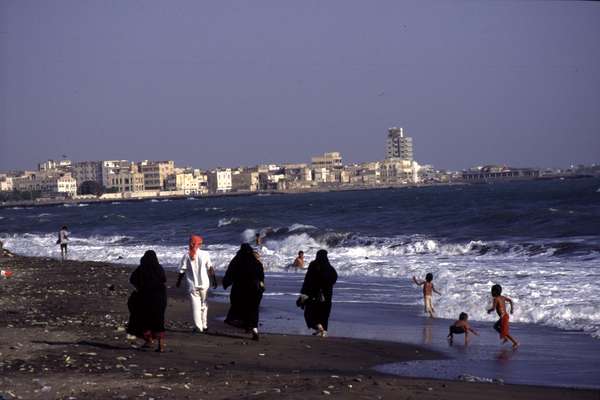 photo of South Yemen, Gulf of Aden, Yemeni man with 3 covered women on the beach of Al Mukalla