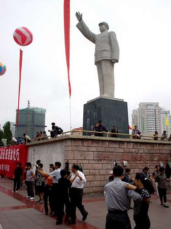 photo of Central China, Guiyang, Guizhou province, a lot of Chinese love to do early morning gymnastics before they go to work, here people are dancing walses below a statue of Mao at 6am in the centre of Guiyang