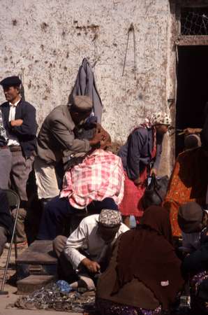 photo of China, Xinjiang province (East Turkistan), Kashi, Uygur man are shaved bold by street hairdressers on the Kashgar Sunday market