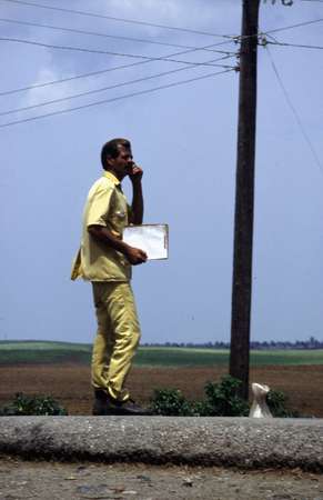 photo of West Cuba, 'el amarillo' in action, this 'yellow man' organises the Cuban hitchhiking, he stops trucks and listens if their excuses are acceptable of not and if not, collects a small payment of farmers and villagers that mount on