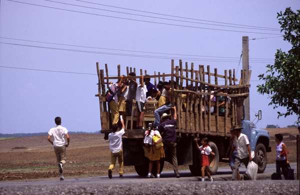 photo of Western Cuba, Cuban villagers and farmers climbing on a truck after a long time waiting along the road for a ride