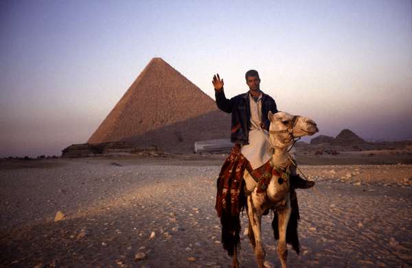 photo of Egypt, Cairo, Egyptian man on a camel in front of the pyramids at Giza
