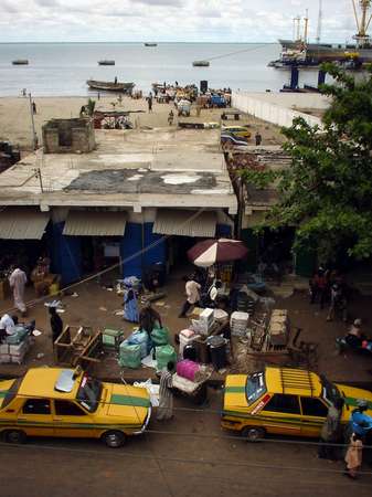 photo of Gambia, Banjul, yellow taxis and market vendors with behind the port and ferry terminal of Banjul