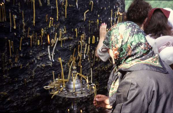 photo of Republic of Georgia, Svaneti, old Georgian woman hanging candles against the church of St. Kvirike in the village of Kala during the celebration of Kvirikoba (end of july)