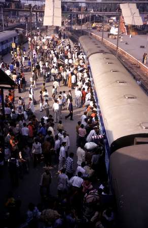 photo of India, New Delhi, train arriving in the Delhi Train Station, people climbing in via the windows and  throwing their luggage inside through the windows to be sure of a good place