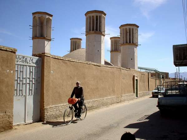 photo of Iran, Yazd, man on bicycle mud brick houses and the 'badghirs' or windtowers. Windtowers are a kind of airco-avant-la-lettre, they funnel and speed up fresh air from the slightest breezes down to cool the interiors of the houses