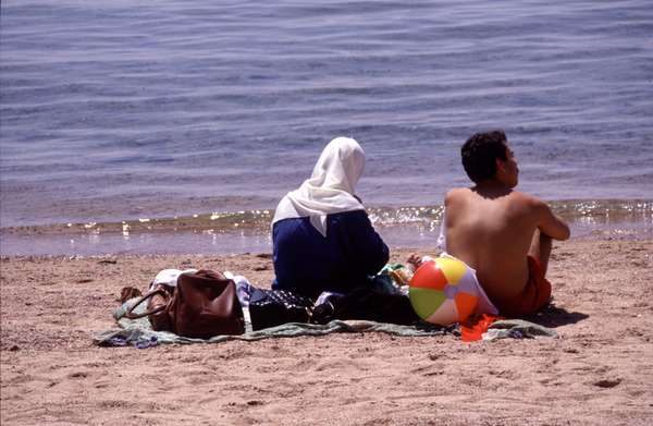 photo of Jordan, Red Sea, Aqaba beach, Jordanian couple staring at the sea, although Jordan is in some ways a very Westernized country, there is still a big segregation between Arab man and woman