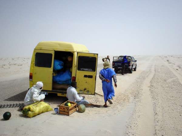 photo of Mauritania, yellow truck with Mauritanians in blue bobo, having a breakdown on the desert road between Western Sahara and the Mauritanian border