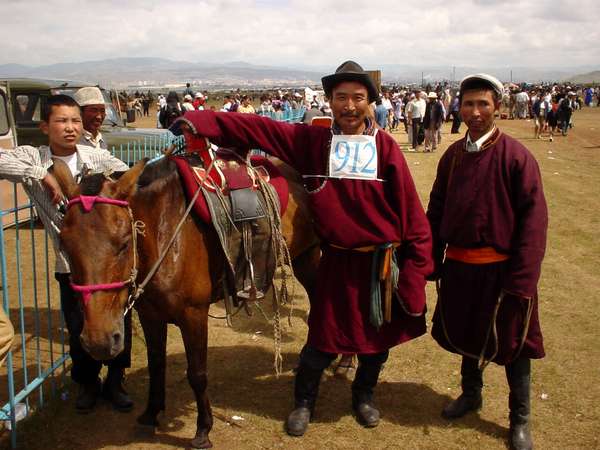photo of Mongolia, in the fields outside Ulaan Baatar (Ulaanbaatar, Ulan Bator), a proud Mongolian horse racing jockey with his horse dressed up for Nadam (Naadam), the Mongolian National holiday