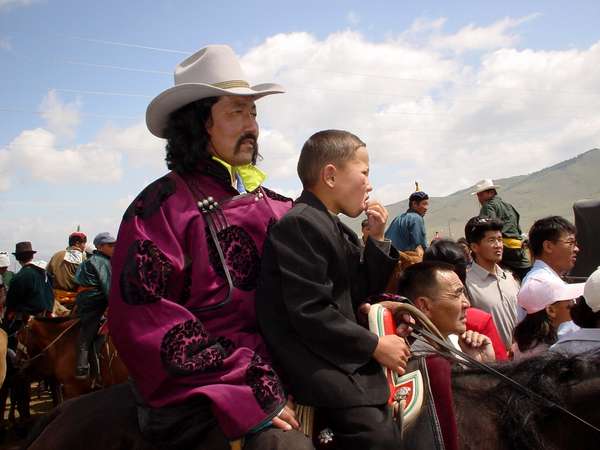 photo of Mongolia, in the fields outside Ulaan Baatar (Ulaanbaatar, Ulan Bator), Mongolian horse racing jockey with his horse and child dressed up for Nadam (Naadam), the Mongolian National holiday