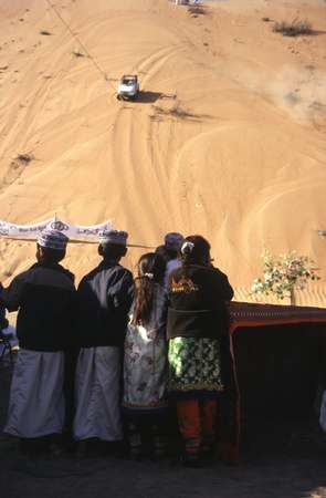 photo of Oman, Wahiba Sands (wahibah desert), around Al Mintirib, Omani children watching 4WD jeeps racing as high as possible up a sand dune