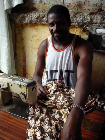photo of Senegal, St.Louis market, Senegalese tailor nitting a colorful shirt in Holland wax (or eurowax) fabric with African clothes design
