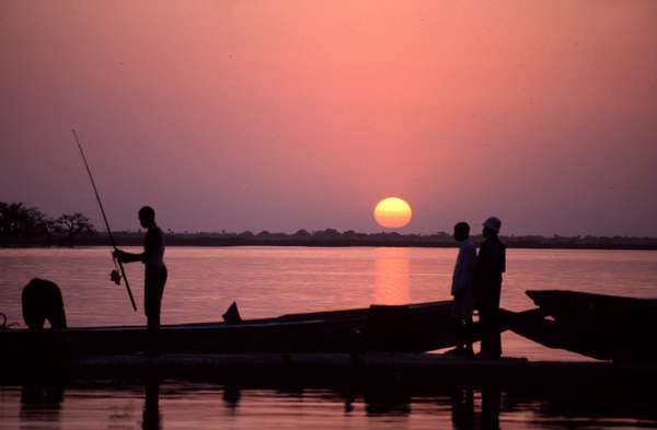 photo of Senegal, Sine Saloum delta, Senegalese fisherman fishing from his pirogue boat at sunset
