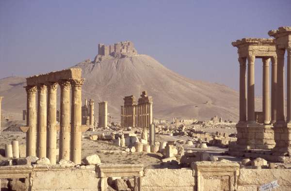 photo of Syria, Syrian desert, ruins of the Roman city of Palmyra (ancient Tadmor), the Great Colonnade and Tetrapylon with the Qala'at ibn Maan (Qalaat) fort on a hill in the background