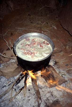 photo of Syria, desert cuisine, mansaf boiling on a fire, traditional nomadic bedouin food dish made with lamb fett chunks (or chicken), rice and yoghurt (of fermented camel milk)