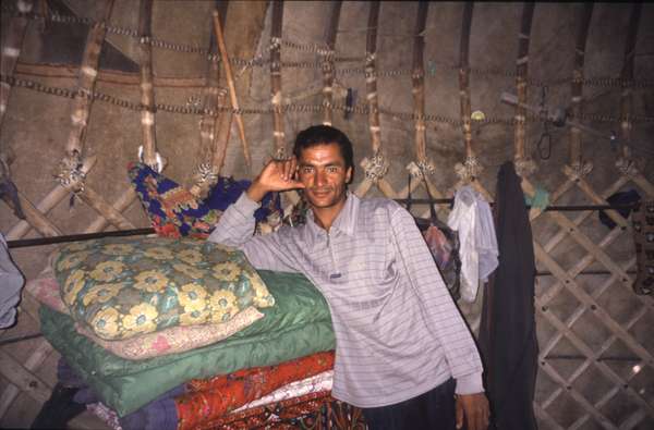 photo of Turkmenistan, Kara Kum desert, Yerbent (Jerbent) village, man with pillows inside a Turkmen yurt (nomads tent)
