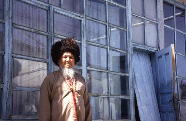 photo of Turkmenistan, mountain village around Nochur, Turkmen man with traditional Turkmen fur hat in front of his house
