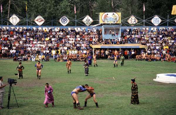 photo of Tuva, Kyzyl, wrestling match, the men perform the dance of the eagle, clad in hand-embroidered garb, and parade in front of spectators. They slap the front and back of their thighs and then spar with a partner trying not to touch the ground except with the palms of their hands or their feet