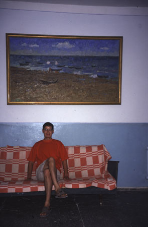 photo of Uzbekistan, around Moynaq (Moynak, Muynak), a former fishing village on the shores of the Aral Sea, owner of the Oybek hotel. Behind him is a painting of 1977 when the fisherman were still happily fishing in the Aral Sea, now the lake is so dried out that its shore has moved more than 100 kilometers away