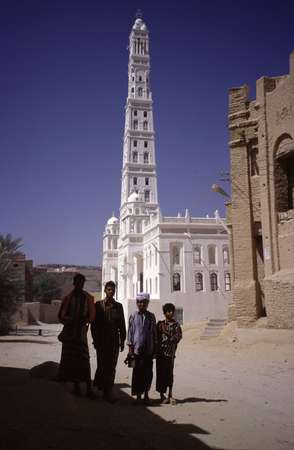 photo of Yemen, Wadi Hadramaut (Hadramaout, Hadhramawt), Tarim, Yemeni people posing in front of white minaret of the  Al-Midhar (Al-Muhdhar) Mosque