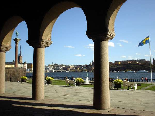 photo of Sweden, Stockholm, view on the water, the Swedish flag an a little part of the Stockholm Old Town from the garden of the Stadshuset (City Hall)