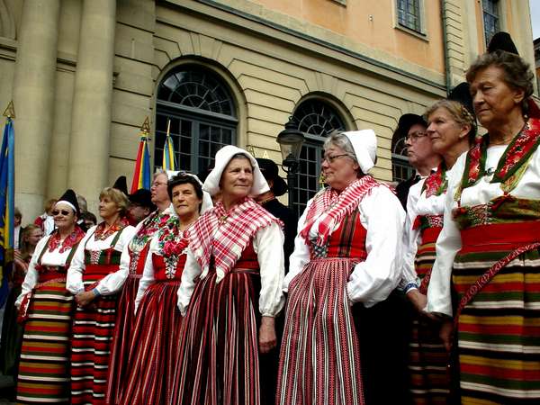 photo of Sweden, Stockholm, Stortorget Gamla Stan, celebration of people from Hälsingland in traditional Swedish dress (folkdräkt), traditional women in red and white striped clothes ready to dance