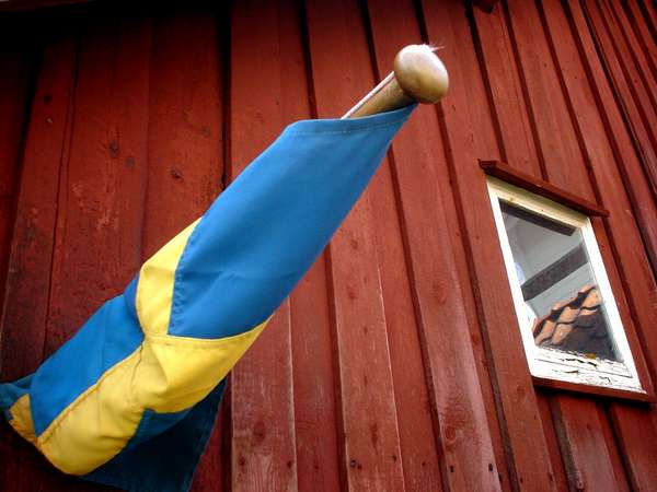 photo of Sweden, Gullholmen, detail of a Swedish flag and a red house with white window