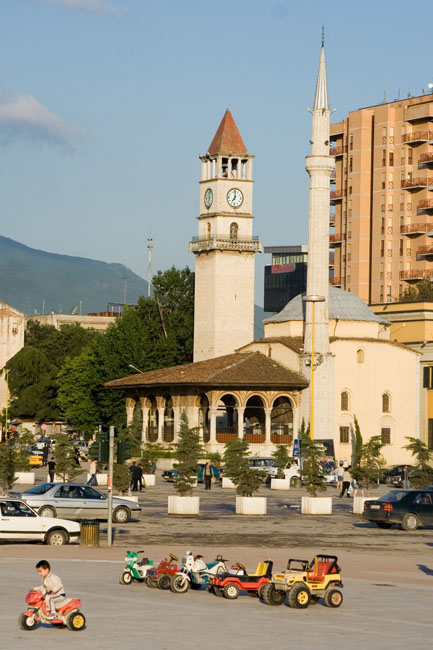 Albania photo of Tirana: Ethem Bey mosque on Sheshi Skënderbej (Skanderbeg square) and clock tower (Kulla e Sahatit). Children play with colourful plastic toy cars in central Tirana city. 